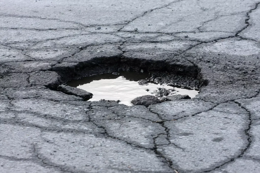 A Georgia road is cracked with a pothole filled with water.
